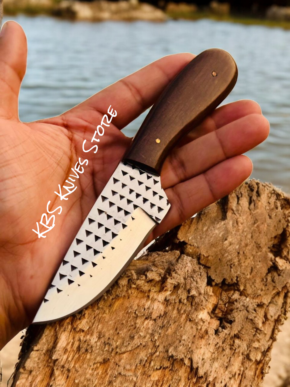 Hand holding a knife with a decorative blade against a natural background