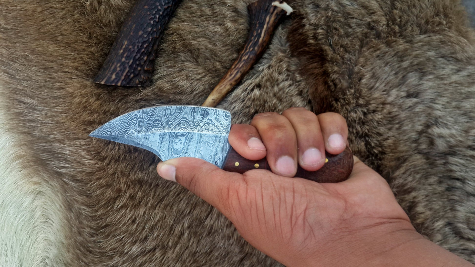 Detail view of the full tang Damascus steel blade of the custom skinning knife, emphasizing its strength and quality.