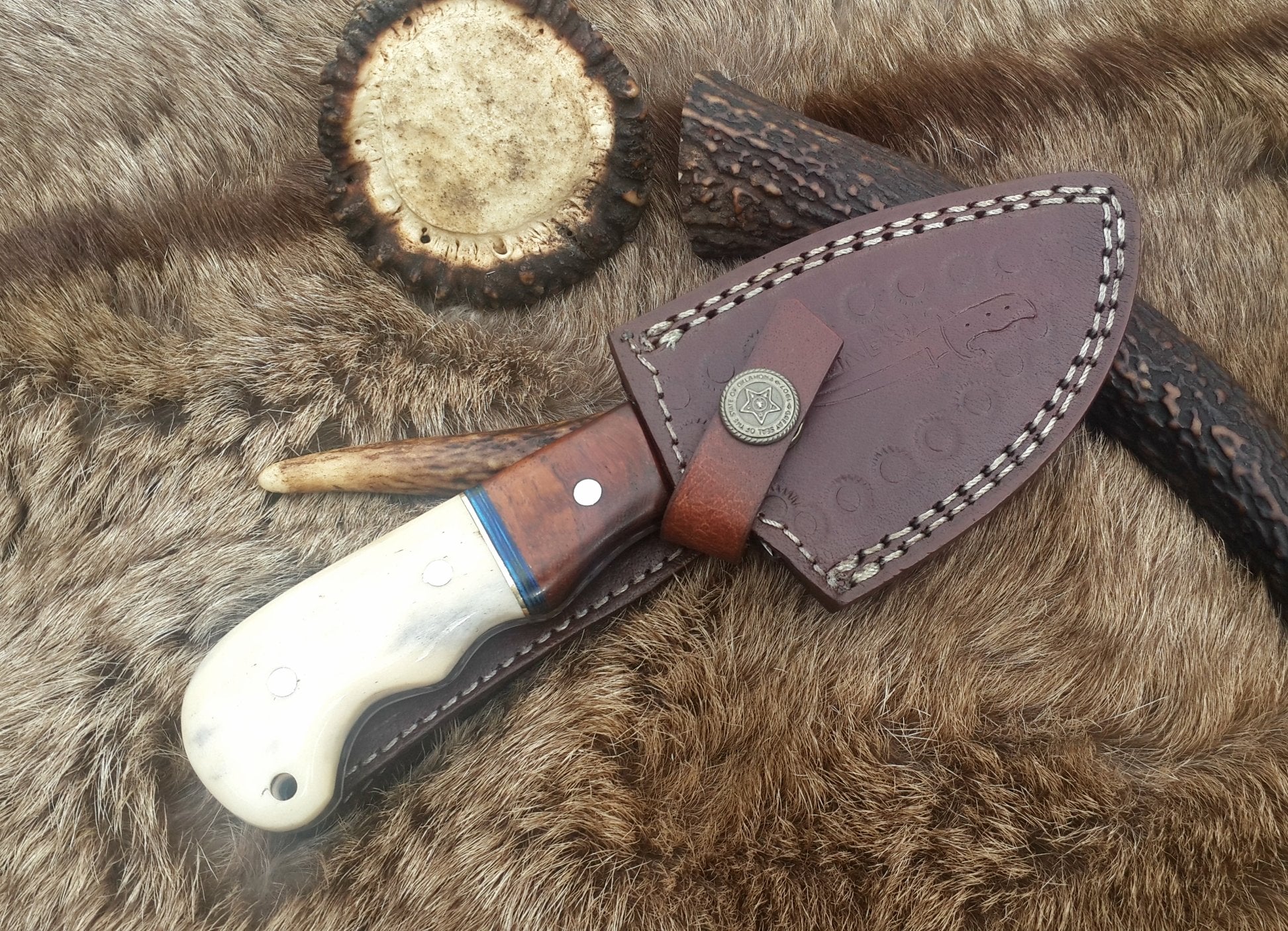 Damascus steel drop point skinning knife displayed outdoors, demonstrating its practical use in the field.