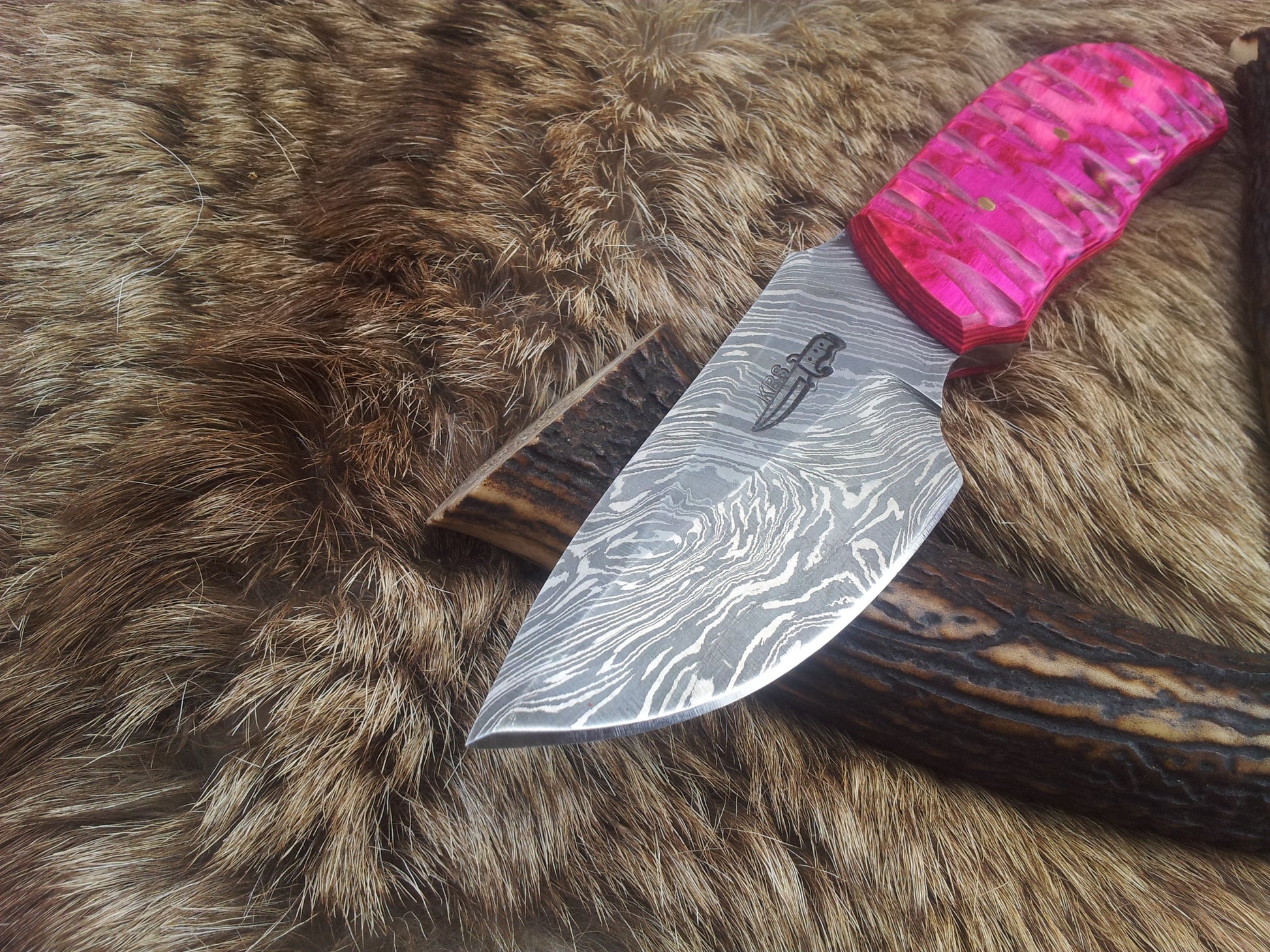 Exotic pink Pakka wood handle of the skinning knife, emphasizing comfort and grip.