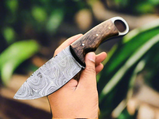 Deer skinning knife with full tang Damascus steel blade and walnut wood handle with finger hole.