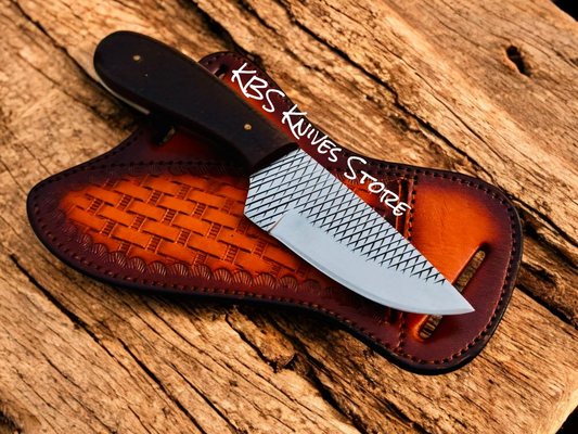 Knife with leather sheath on a wooden surface, branded 'KBS Knives Store'.