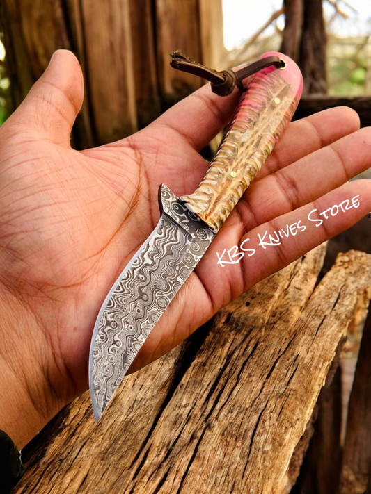 Hand holding a knife with a decorative blade and wooden handle against a natural background.