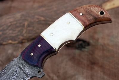 Close-up of G10, bone, and rosewood handle on Damascus steel knife
