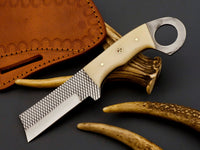 Cowboy castrator knife displayed with a handcrafted leather sheath.
