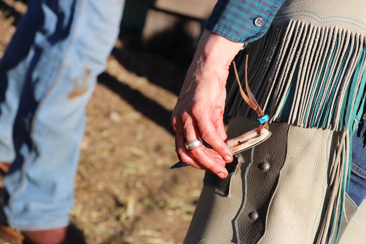 Close-up of a person wearing a fringed leather boot outdoors.
