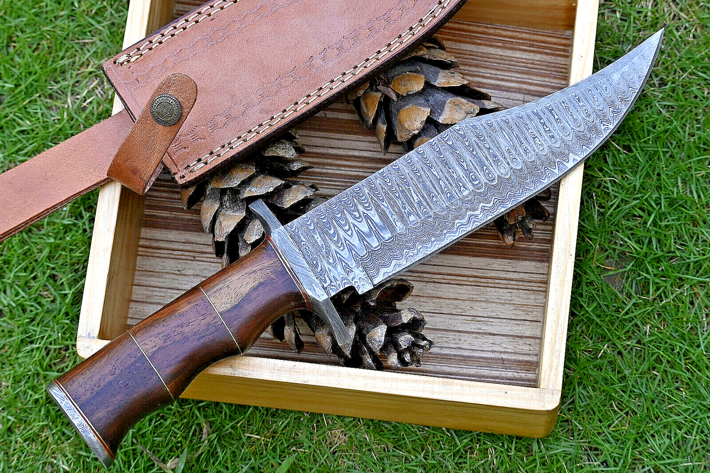 Hunting Bowie knife with Damascus steel blade, Rosewood handle with brass spacers, Damascus guard, and leather sheath. An essential tool for outdoor enthusiasts and hunters alike.