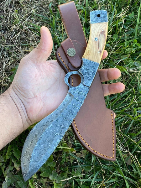 Close-up view of the Raindrop Damascus Steel Kukri Knife with a beautifully carved Olive Wood handle, featuring an intricate Damascus Bolster. The 12-inch blade gleams with a unique pattern. A premium leather sheath is included.