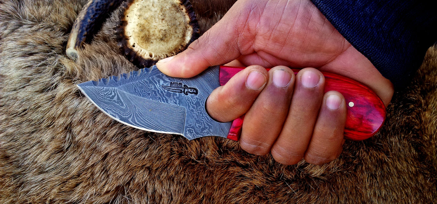 3.5-inch drop point Damascus steel blade close-up with finger hole for precision.
