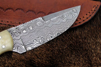 Detailed look at the full tang Damascus steel blade of the fixed blade skinning knife.