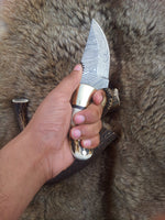 Full view of the 7.25-inch Damascus steel field dressing knife with leather sheath.
