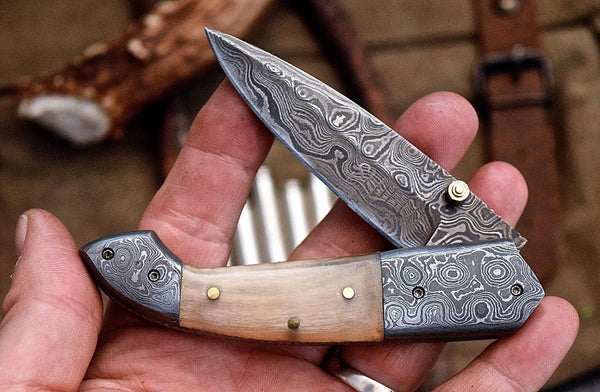 Custom handmade Damascus steel folding knife featuring water buffalo horn handle and detailed Damascus bolsters.