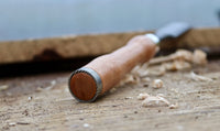 Olivewood handle of the Damascus chisel with brass accents, emphasizing the ergonomic design.
