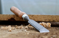 Chisel in action, carving intricate designs on a wooden block, demonstrating its precision and control.