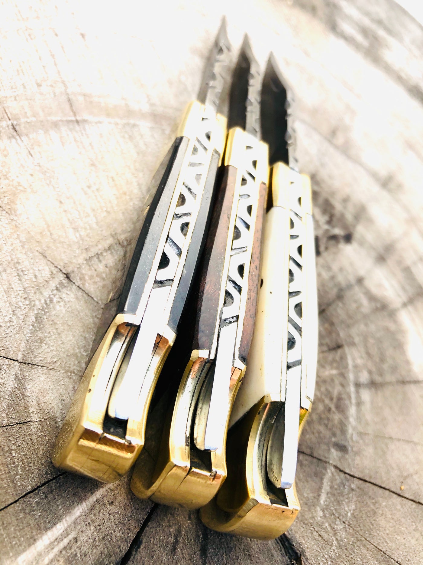 A trio of exquisite folding pocket knives with Damascus steel blades, featuring handles made from buffalo horn, bone, and rosewood, adorned with brass bolsters. Each knife measures 5 inches overall and comes with a stylish leather case for secure storage and portability.